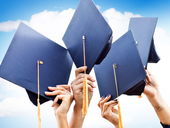 graduation caps held by multiple people in the air