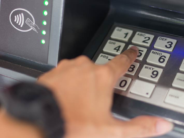 hand entering pin number at ATM