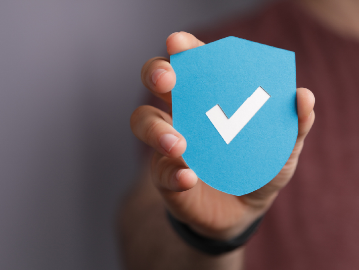 hand holding a light blue security badge with a white checkmark