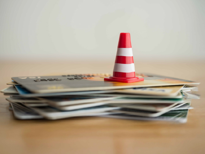 orange and white safety cone over a stack of credit cards